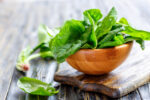 wooden bowl overflowing with fresh spinach