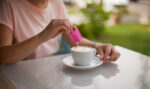 Woman pouring sugar substitute in her coffee