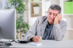 exhausted man sitting in front of computer