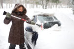 Woman scraping snow off of her car