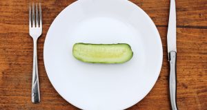 Half a cucumber on a plate with knife and fork