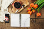 food journal on table with cup of coffee and flowers