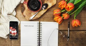 food journal on table with cup of coffee and flowers