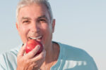 Happy older man eating an apple
