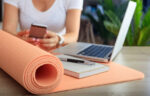 woman with cell phone, laptop, and yoga mat