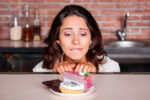 Woman craving piece of cake on a plate