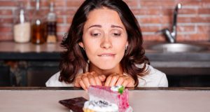 Woman craving piece of cake on a plate