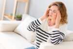 woman with headache sitting on couch
